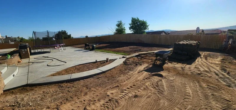 Concrete patio with curved edges during installation, graded soil and wooden forms visible