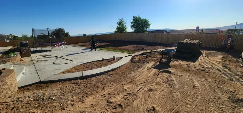 Newly poured concrete patio with curved design on prepared soil base in residential yard
