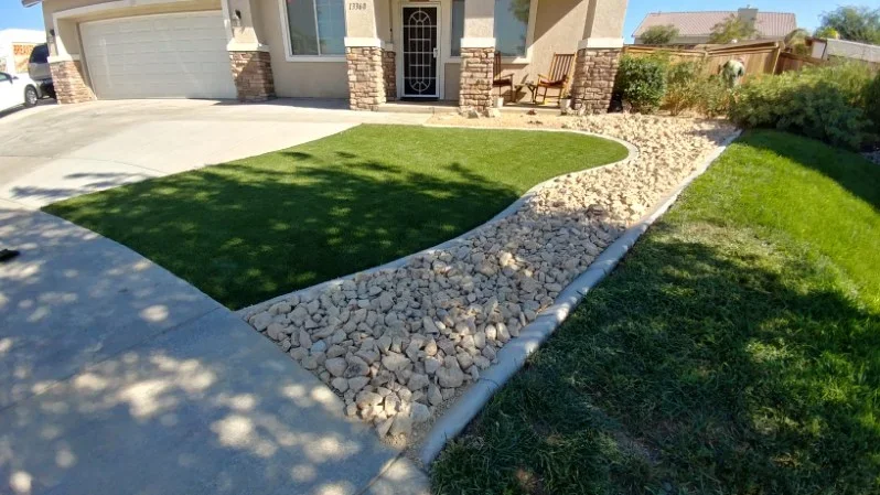 Newly sodded lawn with curved river rock borders and stone edging along residential driveway