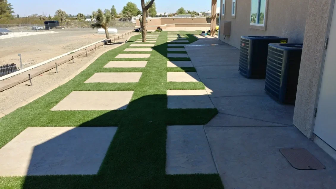 Concrete pavers and synthetic turf strips in alternating pattern with dark patio and mature trees