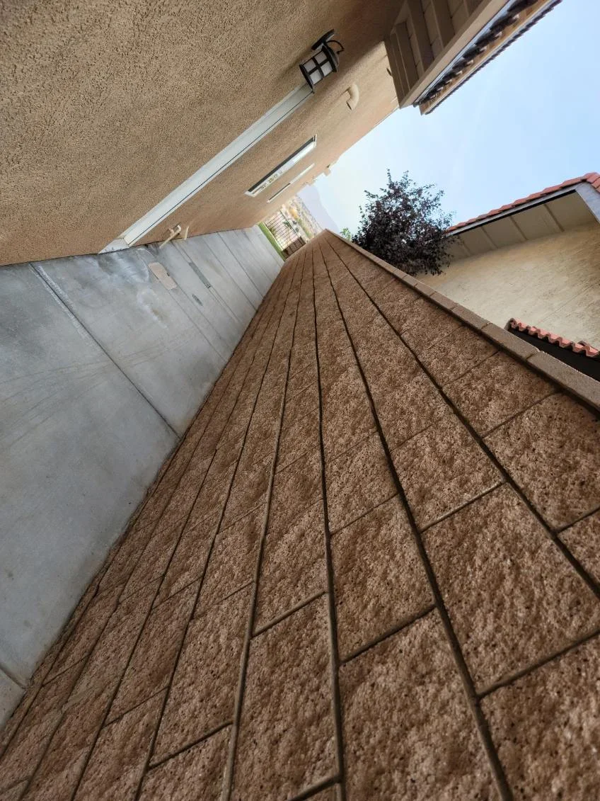 Tan pavers in running bond pattern with metal edging and proper drainage grading